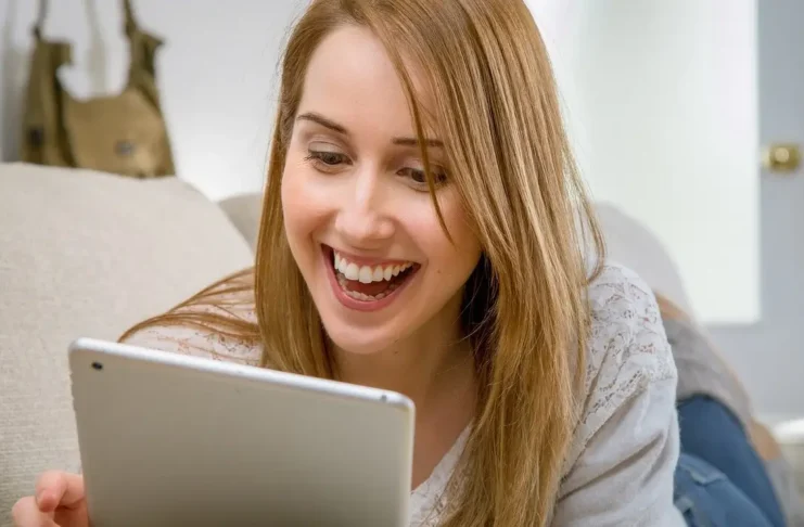 Uśmiechnięta kobieta patrząca w tablet