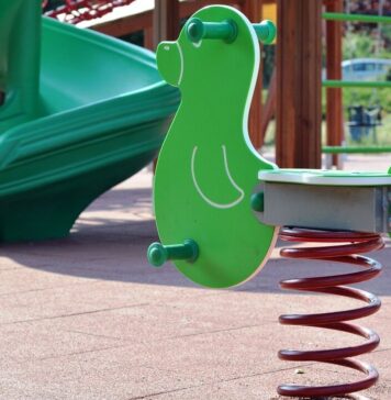 Plac zabaw, na pierwszym planie bujak sprzężynowy w tle zjeżdżalnia