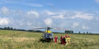 Śmigłowiec LPR na polu, obok strażacy